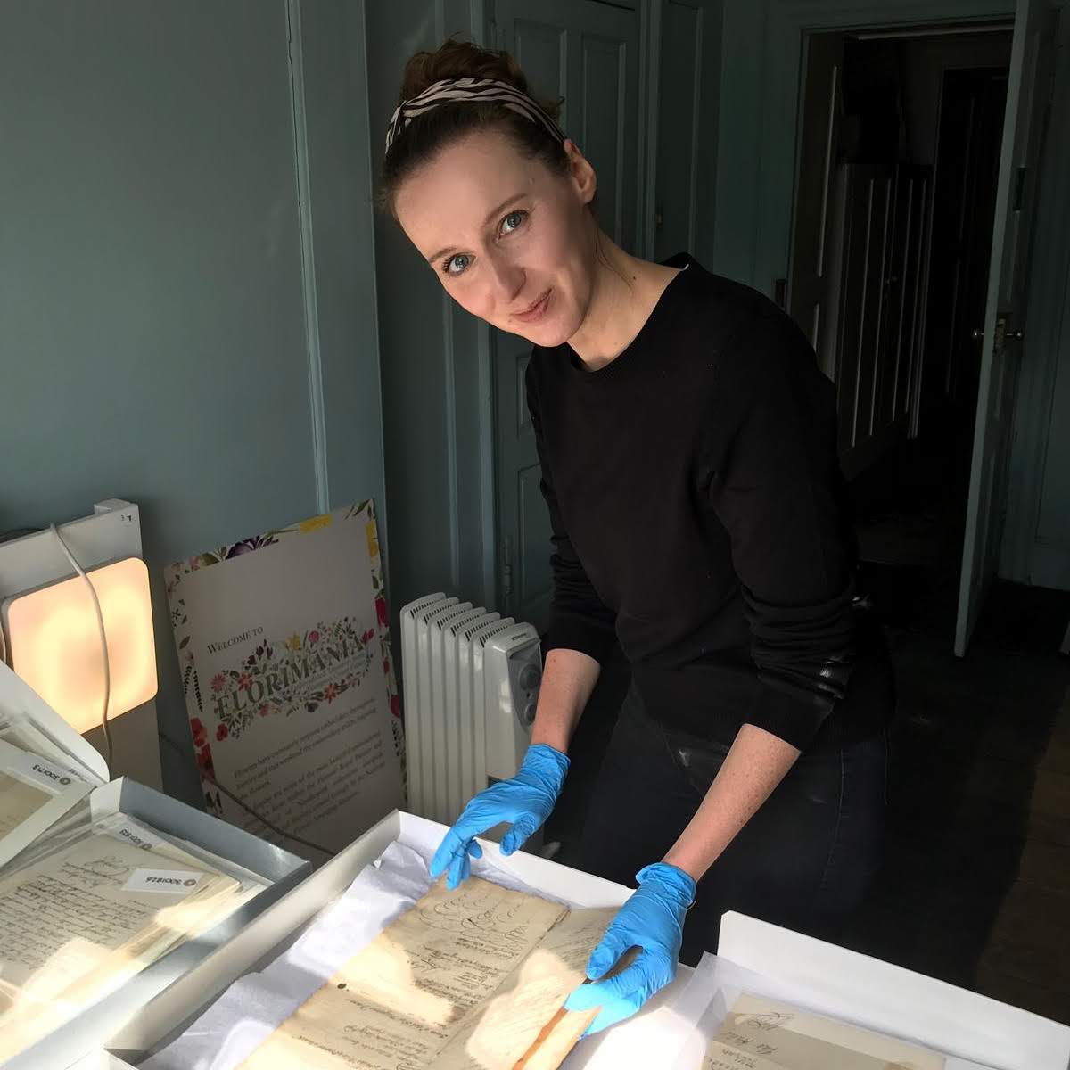 A woman examining manuscripts on a table
